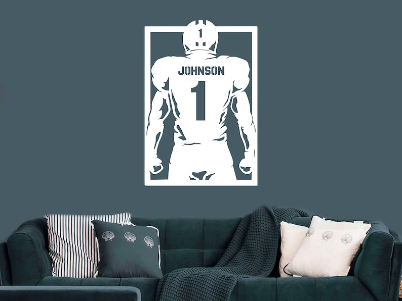 Pu&ograve; includere: Silhouette bianca di un giocatore di football americano che indossa una maglia con il nome "JOHNSON" e il numero "1" sul retro. La silhouette &egrave; all'interno di un rettangolo bianco.