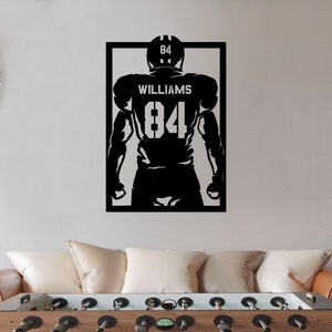 Pu&ograve; includere: Silhouette in bianco e nero di un giocatore di football americano che indossa una maglia con il numero 84 e il nome "WILLIAMS" su di essa.