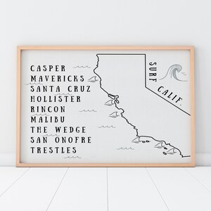May include: A framed wall art print featuring a black line map of California on a white background. The text lists surf spots including Casper, Mavericks, Santa Cruz, Hollister, Rincon, Malibu, The Wedge, San Onofre, and Trestles, with the text SURF CALIF.