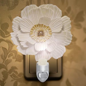 May include: White porcelain night light shaped like a flower with gold accents. The light has an on/off switch.