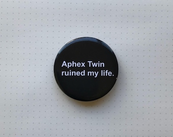 May include: A black button with white text that reads "Aphex Twin ruined my life."