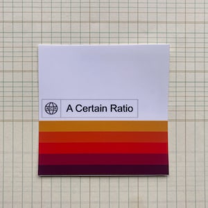 May include: A white sticker with a logo of a globe with the letters "ACR" inside. The text "A Certain Ratio" is below the logo. The sticker has a multi-colored stripe design in shades of orange, red, and purple.