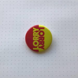 May include: A red and yellow button with the word "LORRY" written vertically in red on the left side and "HORRY" written vertically in yellow on the right side.