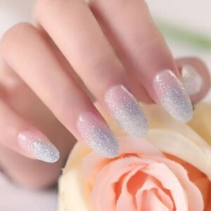 May include: Close-up of a hand with oval-shaped nails painted with a silver glitter polish. The hand is holding a light pink rose.