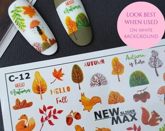 Puede incluir: Una hoja de pegatinas para uñas con temática otoñal. Las pegatinas presentan imágenes de hojas, árboles, ardillas, bellotas y el texto "Hello Autumn", "Hello Fall" y "Autumn is here".