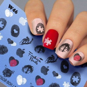 May include: Nail art stickers with a blue background and various designs, including fingerprints, hearts, apples, and puzzle pieces. The text "Fashion Nails" is printed on the sheet. The sticker sheet is labeled "W46".