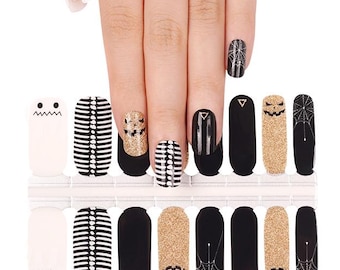 May include: Halloween-themed nail wraps featuring various designs. The wraps include white ghost faces, black and white striped patterns, gold glitter, and black nails with spiderwebs and triangles. The nail wraps are displayed on a white background.