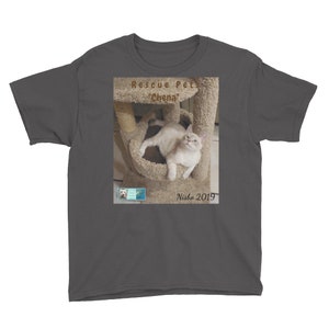 May include: A charcoal grey youth t-shirt with a photo of a white cat in a cat tree. The text "Rescue Pet "Chena" Nisbe 2019" is printed on the shirt.
