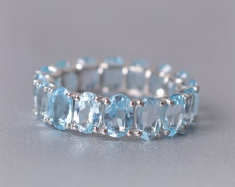 May include: A silver ring with a row of oval-shaped light blue gemstones.