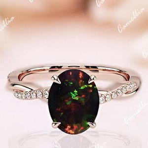 May include: A rose gold engagement ring with a black opal gemstone and a twisted band accented with small diamonds.