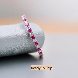 Op de afbeelding: Een delicate eeuwigheidsring met een rij van afwisselende roze en witte edelstenen. De ring is gezet in zilver.