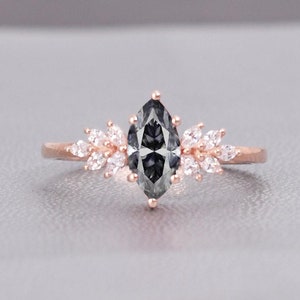 May include: A rose gold engagement ring with a marquise-shaped grey diamond and a delicate floral design.