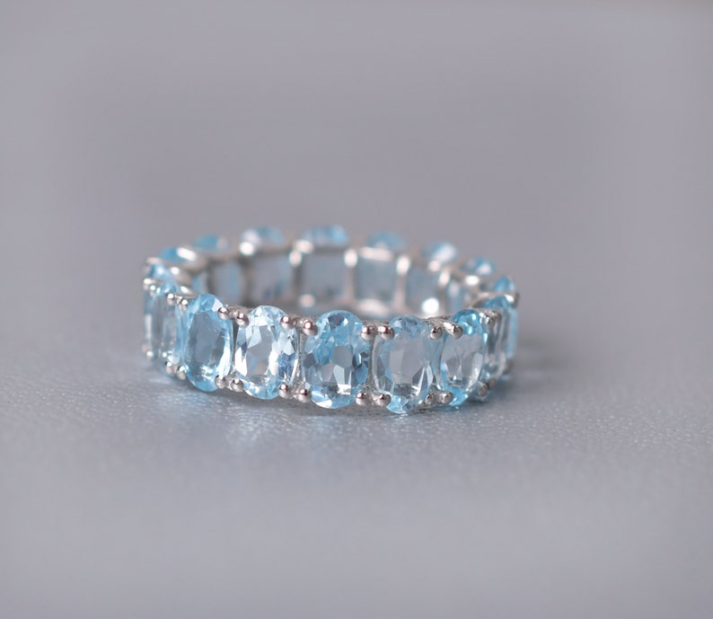 May include: A silver ring with a row of oval-shaped light blue gemstones.