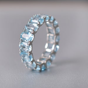 May include: A silver ring with a row of oval-shaped light blue gemstones.