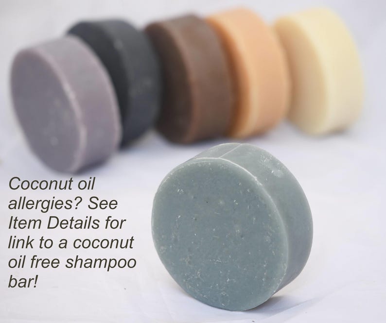 K&ouml;nnte beinhalten: Sechs runde Seifenst&uuml;cke in verschiedenen Graut&ouml;nen, Braun- und Beiget&ouml;nen. Die Seifenst&uuml;cke sind in einer Reihe angeordnet, wobei das graue St&uuml;ck im Vordergrund steht. Der Text "Coconut oil allergies? See Item Details for link to a coconut oil free shampoo bar!" steht unter den Seifenst&uuml;cken.