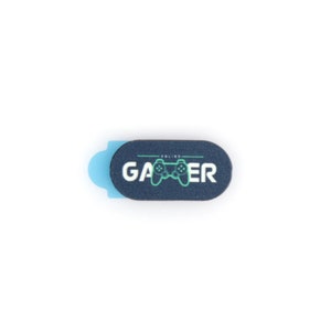 May include: A black webcam cover with a blue adhesive strip. The cover has a green and black gamepad graphic and the text "ONLINE GAMER".