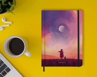 May include: A rectangular notebook with a black elastic closure featuring a printed illustration of a person and a small animal standing in a field under a purple and pink sky with a moon. The word matabooks is printed at the bottom center.