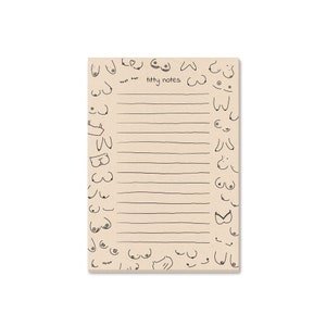 Puede incluir: Un bloc de notas marrón con un interior rayado y una ilustración en blanco y negro de senos en la portada. El bloc de notas tiene el texto "titty notes" impreso en la portada.