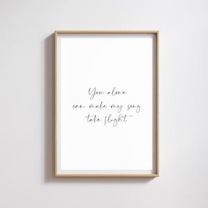 May include: A rectangular wall art print in a light wood frame featuring a white background with black cursive text that reads: You alone can make my song take flight. The print is centered within the frame, which has a simple, clean edge.