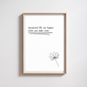 May include: A framed art print with a white background. The print features the text "unexpected life can happen when you make room" in black, with a line drawn underneath. A black and white flower illustration is in the lower right corner.