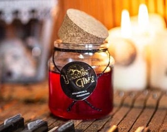 May include: A glass jar with a cork lid filled with a red liquid and a black label that reads "Dramatic Glow". The jar is sitting on a vintage piano with white and black keys.