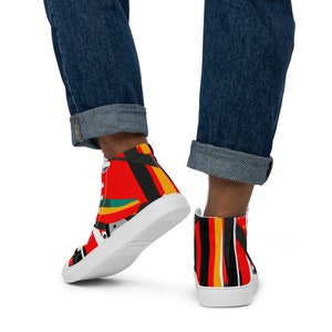 Op de afbeelding: Hoge sneakers met een levendig abstract ontwerp. De schoenen hebben een witte zool en een kleurrijk patroon van rode, zwarte, gele en turquoise vormen. De veters zijn wit en de algehele stijl is modern en opvallend.
