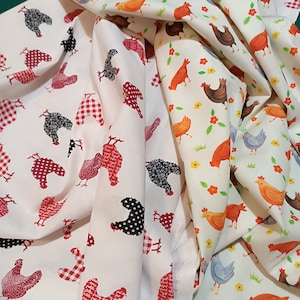 Könnte beinhalten: Zwei weiße Stoffbahnen mit einem sich wiederholenden Muster aus roten und schwarzen Hühnern. Der Stoff ist so gefaltet, dass das Muster auf beiden Seiten sichtbar ist.