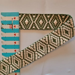 Puede incluir: Cinta tejida con un patr&oacute;n de diamantes repetido en blanco y verde oliva. La cinta se mide con una regla azul y blanca. La cinta mide aproximadamente 3,8 cm de ancho.