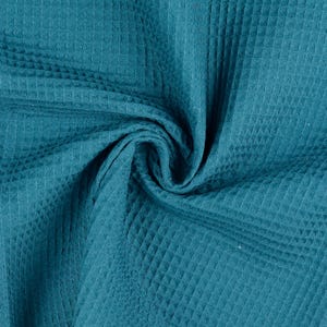 Könnte beinhalten: Tealfarbener Waffelstoff mit einem strukturierten, gesteppten Muster. Der Stoff ist gefaltet und drapiert und zeigt seine weiche und geschmeidige Textur.