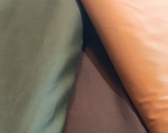May include: Close-up of three fabric swatches in different shades of brown, green, and orange. The fabric has a smooth, silky texture.