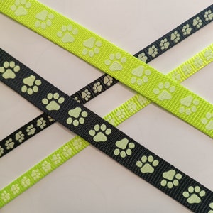 Könnte beinhalten: Zwei grüne und ein schwarzes Band mit einem Pfotenabdruck-Design. Die Pfotenabdrücke sind hellgrün.