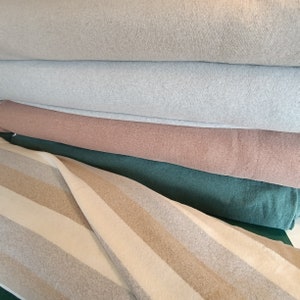 Könnte beinhalten: Ein Stapel Stoffmuster in verschiedenen Farben und Texturen, darunter Beige, Hellgrau, Braun, Grün und ein gestreiftes Muster.