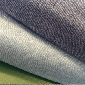 Könnte beinhalten: Zwei Stücke Jeansstoff, eines hellblau und eines dunkelblau, liegen übereinander gefaltet. Der Stoff hat eine gewebte Textur.