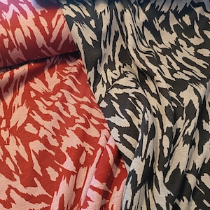 Könnte beinhalten: Zwei Stoffstücke mit einem schwarz-weißen Tiermuster und einem rot-weißen Tiermuster.