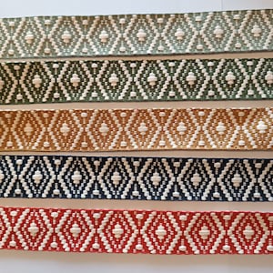 Puede incluir: Primer plano de seis cintas tejidas con un patr&oacute;n de diamantes repetido. Las cintas son de varios colores: verde claro, verde oscuro, dorado, azul marino y rojo. El patr&oacute;n de diamantes es blanco.