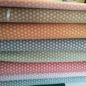 Könnte beinhalten: Ein Stapel Stoffrollen mit einem geometrischen Muster. Der Stoff ist in verschiedenen Farben, darunter Braun, Orange, Blau, Grün, Rot, Lila und Türkis.