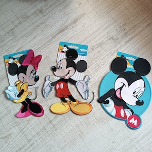 Könnte beinhalten: Drei Bügelbilder mit Mickey Mouse. Das erste Bügelbild ist eine pinkfarbene und weiße Minnie Mouse mit einer roten Schleife. Das zweite Bügelbild ist ein roter und gelber Mickey Mouse mit schwarzen Umrissen. Das dritte Bügelbild ist ein blauer und weißer Mickey Mouse mit schwarzen Umrissen.