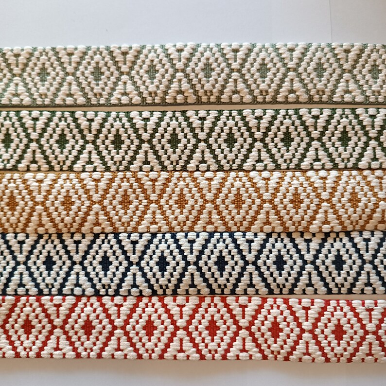Puede incluir: Primer plano de seis tiras de tela tejida con un patr&oacute;n de diamantes repetido. Los colores incluyen blanco roto, verde oliva, amarillo mostaza, azul marino y rojo, cada uno con un dise&ntilde;o de diamante blanco. Las tiras est&aacute;n dispuestas horizontalmente.