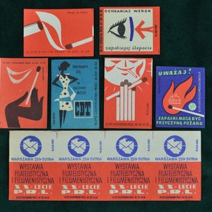 Könnte beinhalten: Eine Sammlung polnischer Vintage-Streichholzschachteln mit farbenfrohen Designs und Texten. Die Streichholzschachteln zeigen Illustrationen einer Frau, eines Auges, einer Sonne und eines brennenden Hauses. Der Text enthält polnische Sätze und die Wörter "Warschau" und "Ausstellung".