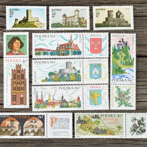 Op de afbeelding: Een verzameling vintage Poolse postzegels met verschillende kastelen, bezienswaardigheden en historische figuren. De postzegels zijn in verschillende kleuren en ontwerpen, waaronder rood, blauw, groen en geel. De postzegels zijn gerangschikt in een rasterpatroon op een houten oppervlak.