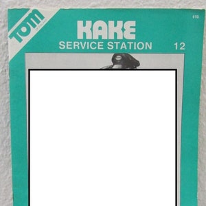 May include: A turquoise blue magazine cover with the title "KAKE SERVICE STATION" in white text. The magazine cover also features a black and white photo of a person wearing a hat and a black jacket.