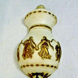 May include: A white ceramic wall fountain with gold accents. The fountain features a decorative top with a spout and a lower basin with a design of dancing figures.