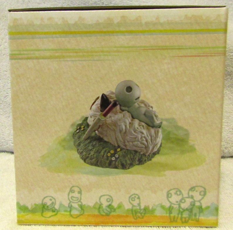 May include: A small, gray, ceramic figurine of a creature with a large head and a small body. The creature is lying on its back on a white, fluffy cloud. The cloud is surrounded by green grass and small, white flowers. The figurine is part of a set of similar figurines.