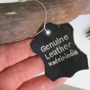 May include: A black leather tag with white text that reads "Genuine Leather Made in India".