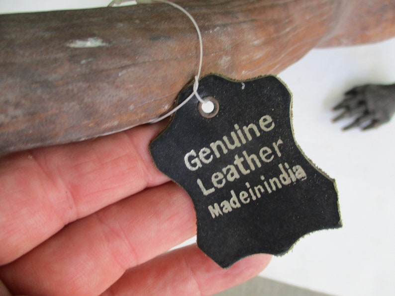 May include: A black leather tag with white text that reads "Genuine Leather Made in India".