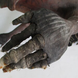 May include: A close-up of a hand, wrapped in dark fabric, with visible stitching. The hand is part of a larger anatomical model, likely for medical or educational purposes.