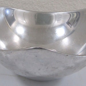 Puede incluir: Un taz&oacute;n de metal plateado con un borde redondeado ligeramente ondulado. El taz&oacute;n es liso y reflectante.