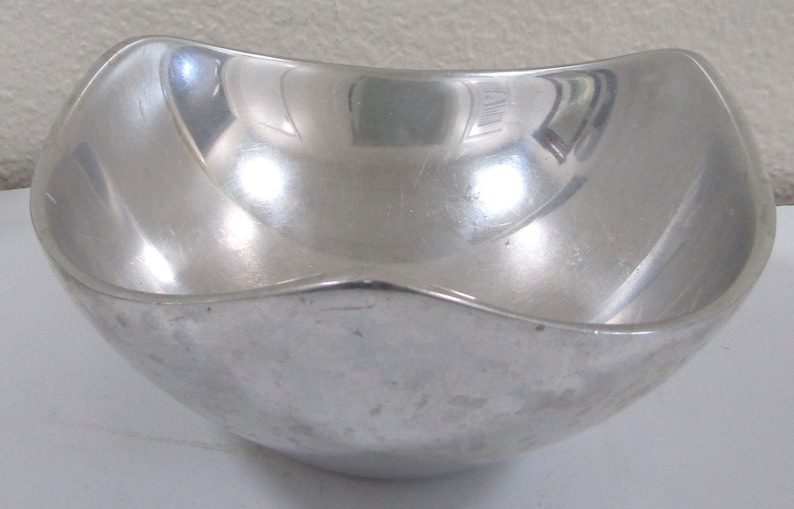 Puede incluir: Un taz&oacute;n de metal plateado con un borde redondeado ligeramente ondulado. El taz&oacute;n es liso y reflectante.