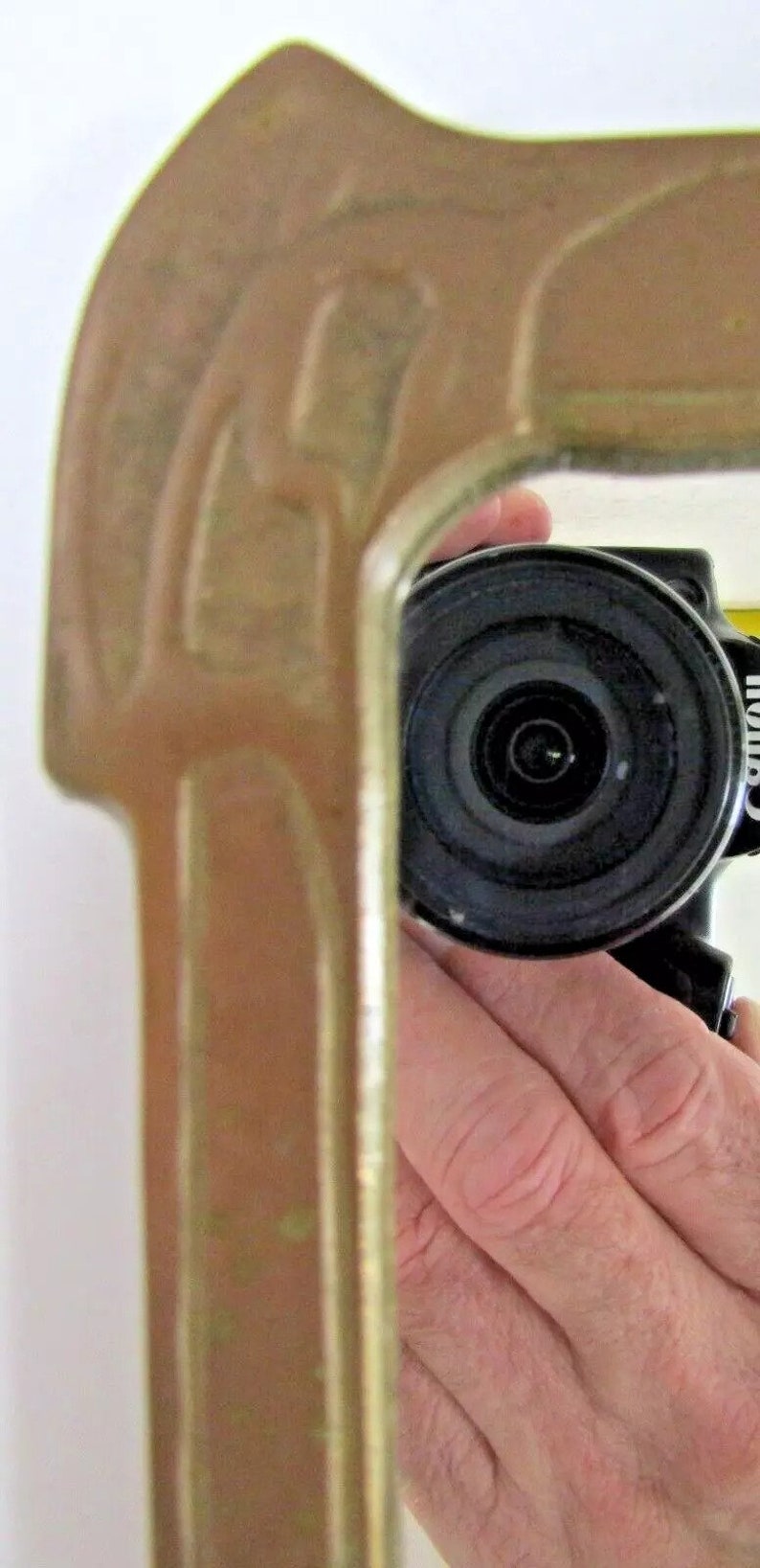 May include: A close-up of a black camera lens with a silver ring around the lens. The camera is being held by a hand.