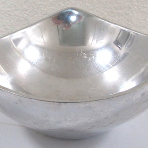 Puede incluir: Un taz&oacute;n de metal plateado con un dise&ntilde;o curvo &uacute;nico. El taz&oacute;n es liso y reflectante.